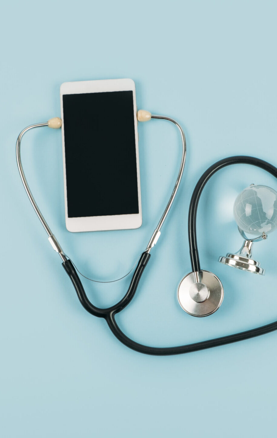 Telemedicine or telehealth virtual visit, video visit, remote doctor video chat consultation concept with smartphone, open notepad and stethoscope on blue background